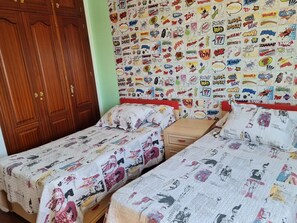 Ein Schlafzimmer mit zwei Betten, einem Holzschrank und einer Wand mit Comic-Aufklebern.