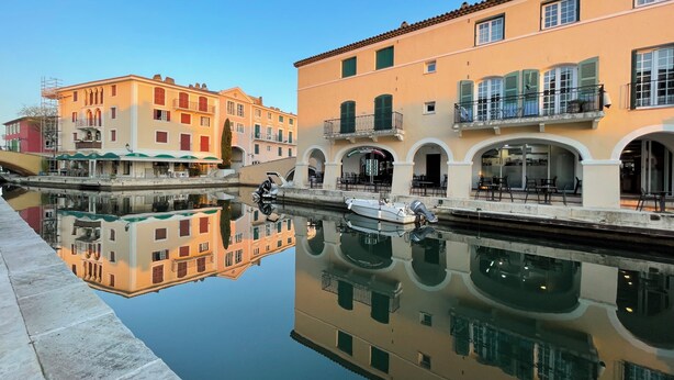 Un canal con un barco amarrado, edificios con balcones y cielo despejado.