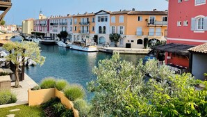 Un canal con barcos, edificios coloridos y vegetación a orillas.
