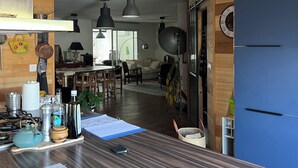 Ett modernt kök med en bänkskiva i trä, hängande taklampor och ett blått kylskåp.