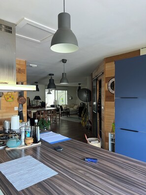 A modern kitchen with a wooden countertop, hanging pendant lights, and a blue refrigerator. - 4-Bedroom House—Pool—Private Parking, Air Conditioning, Historic City Center 10-Minute Walk Away (Bergerac)