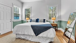 A bedroom with a bed, two bedside tables, a mirror, and a window with blinds. - New! 2 bedroom/2 bath water access cabin at Lake Martin! Sleeps 8! (Dadeville)