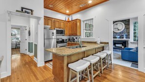 A kitchen with wooden cabinets, a granite countertop, and a built-in island with bar stools. - New! 2 bedroom/2 bath water access cabin at Lake Martin! Sleeps 8! (Dadeville)
