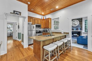 A kitchen with wooden cabinets, a granite countertop, and a built-in island with bar stools.