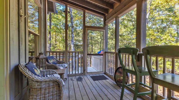 A wooden deck with wicker furniture and a green chair. - New! 2 bedroom/2 bath water access cabin at Lake Martin! Sleeps 8! (Dadeville)