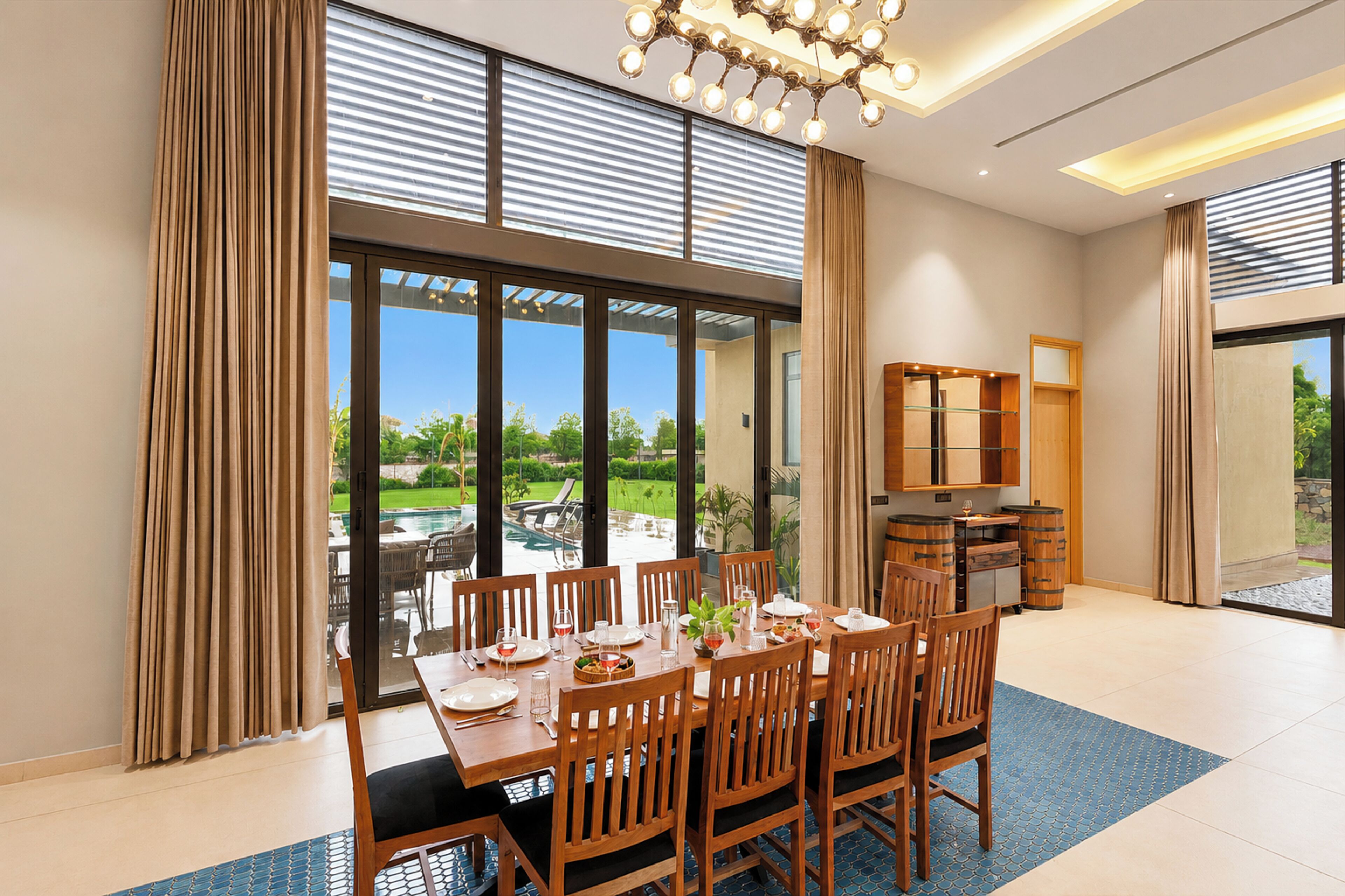 Un coin repas avec une table dressée pour six personnes, de grandes fenêtres et une vue sur l’extérieur.