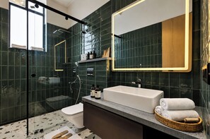 A modern bathroom with a glass shower enclosure, a white bathtub, and a large mirror. - ELIVAAS 24 Carat 4BHK Villa with Pool (Jaipur)