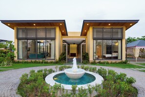 A modern building with a central courtyard, a fountain, and a covered seating area. - ELIVAAS 24 Carat 4BHK Villa with Pool (Jaipur)