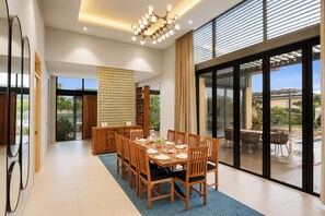 A dining area with a large table, chairs, and a view of the outdoors. - ELIVAAS 24 Carat 4BHK Villa with Pool (Jaipur)