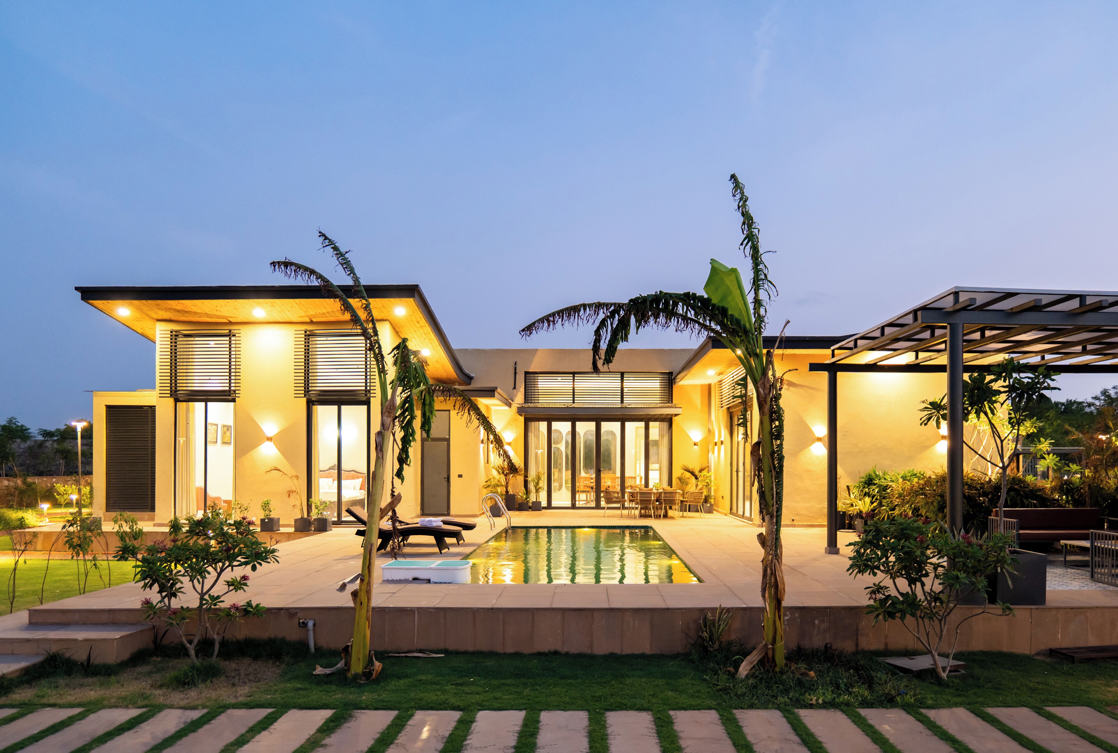 Una casa moderna con piscina, mobiliario exterior y un jardín bien cuidado.
