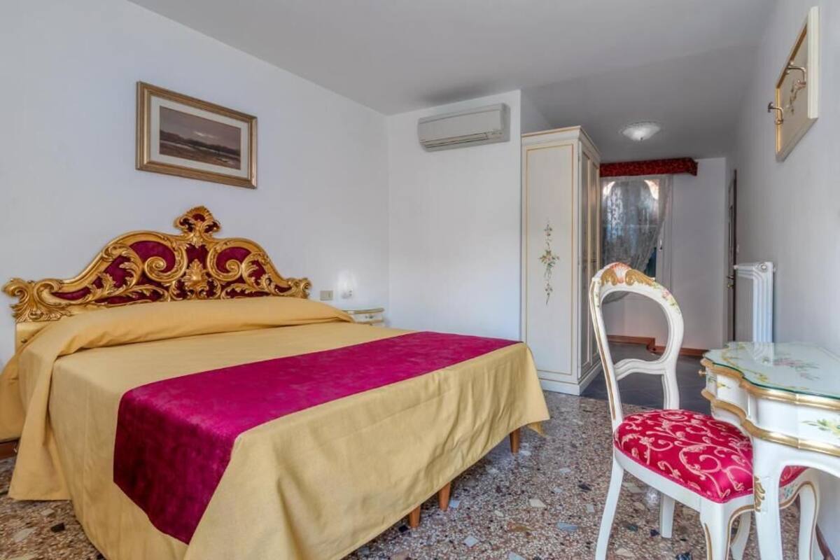 A bedroom with a bed, a chair, a table, and a picture on the wall.