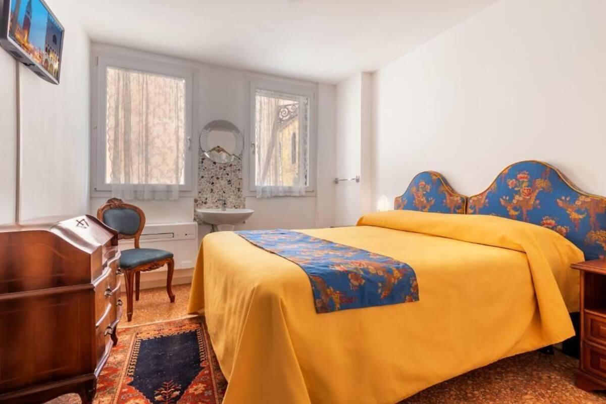 A bedroom with a bed, a dresser, a chair, a desk, and a window with curtains.