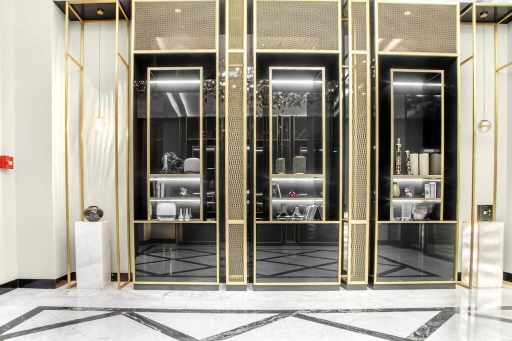 Een modern interieur met een kleurenschema in zwart en goud, met een glazen scheidingswand met planken en een marmeren vloer.