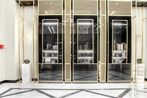 Um interior moderno com esquema de cores preto e dourado, apresentando um painel de vidro central com prateleiras e piso de mármore.
