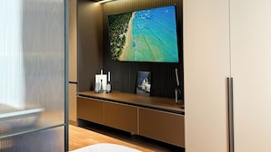 A modern room with a large flat-screen TV mounted on a dark wall, a wooden floor, and a sliding glass door. - Nest One (Tashkent)