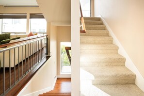 A staircase with carpeted steps and a wooden handrail, leading to a room with a view of the outdoors. - 3-bedroom, 4-bed townhome, steps from Downtown Houston (HOUSTON)
