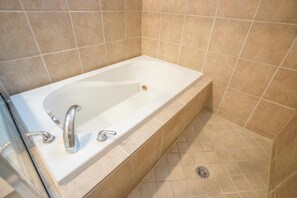 A rectangular bathtub with two faucets, beige tiled walls, and a drain. - 3-bedroom, 4-bed townhome, steps from Downtown Houston (HOUSTON)