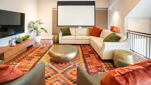 Ein modernes Wohnzimmer mit Flachbildfernseher, einem weißen Sofa, einem gemusterten Teppich und einem Couchtisch.