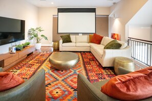 A modern living room with a flat-screen TV, a white sofa, a patterned rug, and a coffee table. - 3-bedroom, 4-bed townhome, steps from Downtown Houston (HOUSTON)