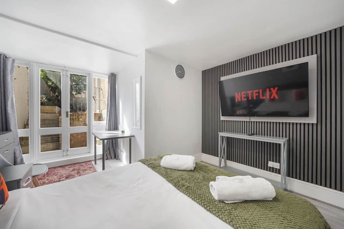 A hotel room with a bed, a desk, a TV, and a view of the outdoors.
