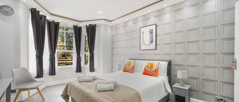 A modern bedroom with a bed, bedside table, and a desk with a chair.