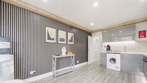 A modern kitchen with a washing machine, a water dispenser, and a sink. - The Cozy Stays Hackney House (London)