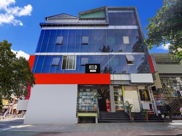 A modern hotel with a glass facade, a prominent red and white base, and a sign indicating it is a company service hotel.