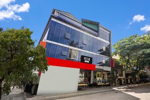 A modern hotel with a prominent 'HOTELO' sign, large windows, and a red and white facade.