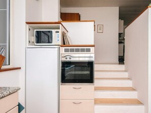 A compact kitchen with a microwave, oven, and refrigerator. - 4 Person Holiday Home in Farvang (Farvang)