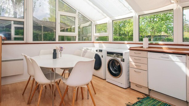 Una cocina moderna con ventanas amplias, una mesa de comedor con sillas y electrodomésticos integrados.