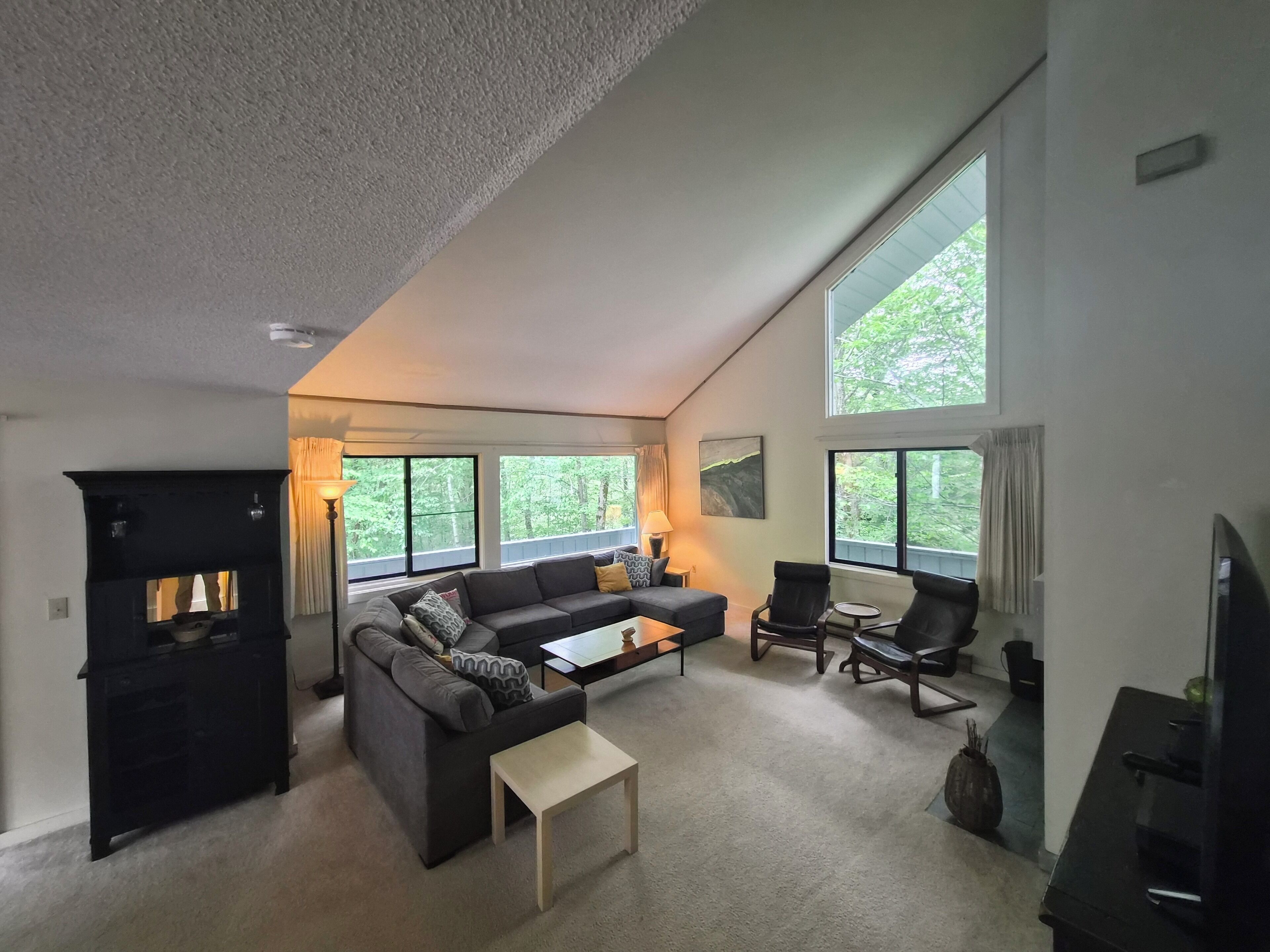 A spacious living room with a fireplace, large windows, a sofa, and a coffee table.