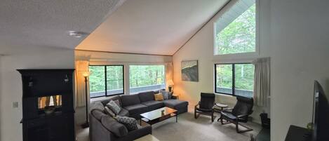 A spacious living room with a fireplace, large windows, a sofa, and a coffee table.