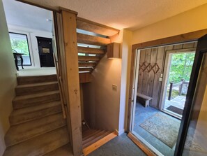 A wooden staircase leading to a second floor, a glass door with a view of the outdoors, and a small bench outside. - Private, stand-alone, updated property, abuts woods, near Loon. C0146 by LRS (Lincoln)