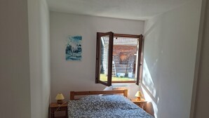 Quarto com uma cama, duas luminárias de cabeceira, uma janela e um quadro na parede.