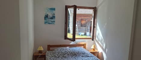Une chambre à coucher avec un lit, deux lampes de chevet, une fenêtre et un tableau au mur.