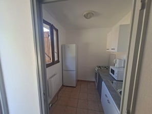 A compact kitchen with a refrigerator, stove, microwave, and cabinets.