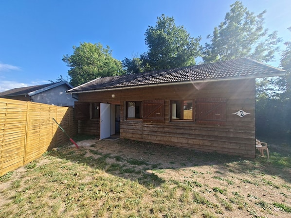A wooden cabin with a tiled roof, a wooden fence, and a number '2' sign.