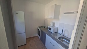 Uma cozinha compacta com geladeira, fogão, micro-ondas e pia.