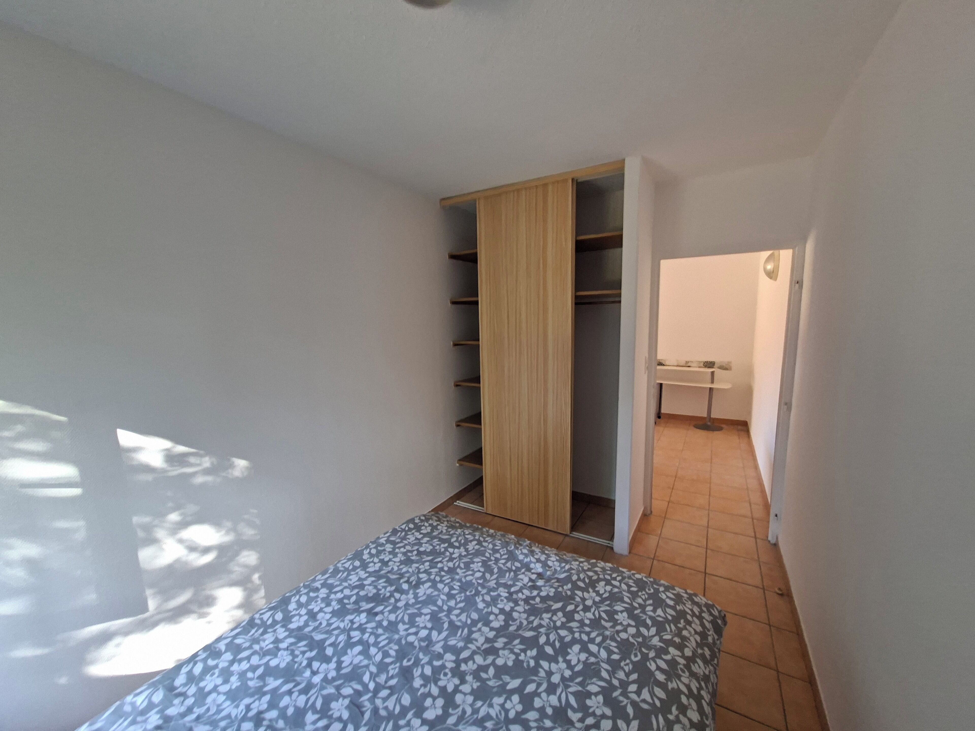 Une chambre à coucher avec un lit, une armoire et une salle de bain visible à travers une porte ouverte.