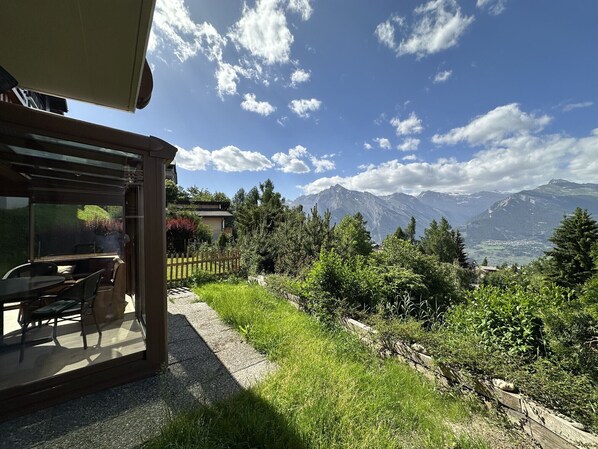 Eine Terrasse mit Sitzgelegenheiten, Blick auf Berge und einem klaren Himmel.