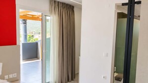 A modern hotel room with a bed, a bathroom, and a sliding glass door leading to a balcony. - New Horizon Sarti - Double Room With Balcony G3 (Sithonia)