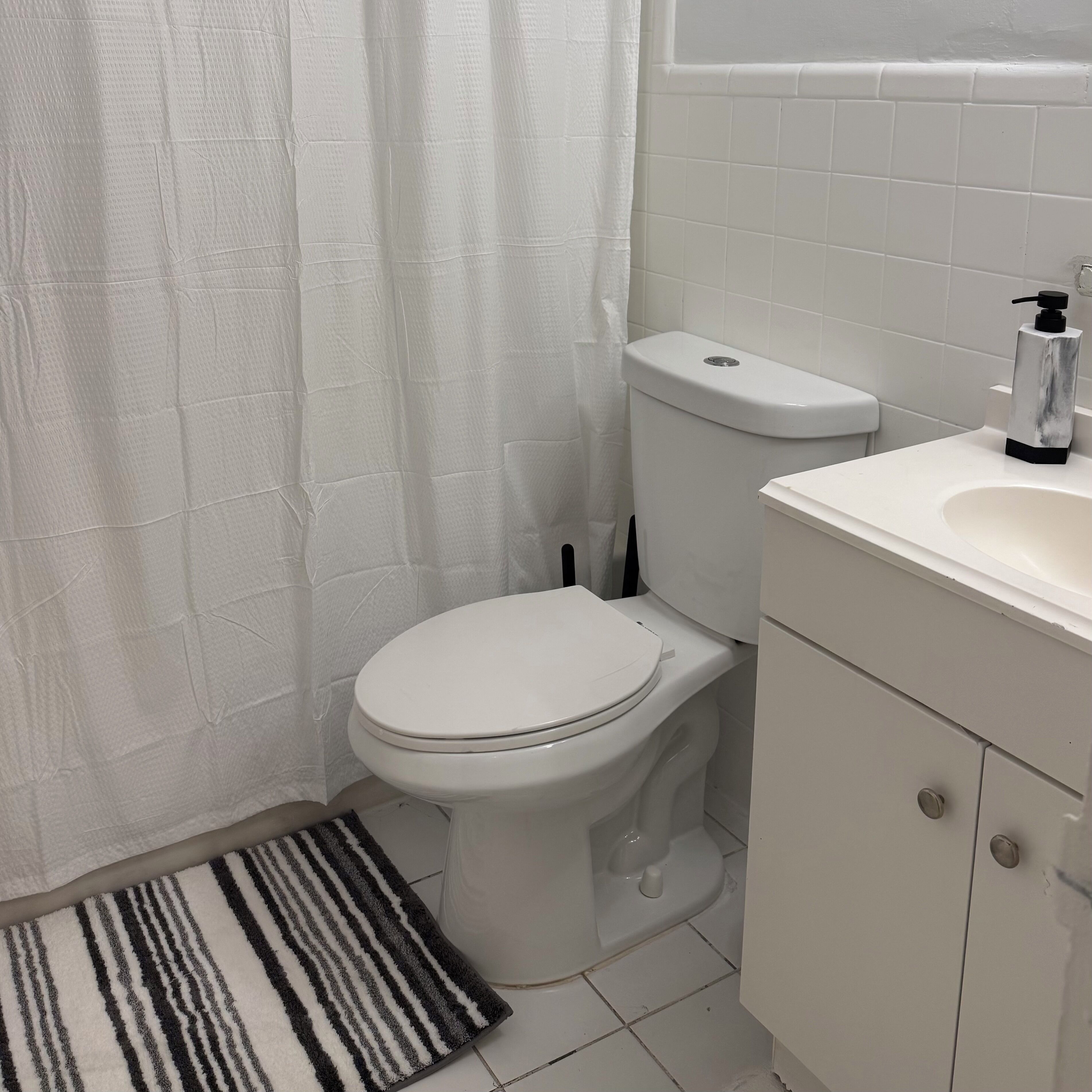 A bathroom with a toilet, sink, and shower curtain.