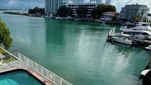 A swimming pool with a hot tub, lounge chairs, and a view of a marina with boats. - Perfect 1-bedroom apartment with AC and free parking in North Bay Village (North Bay Village)