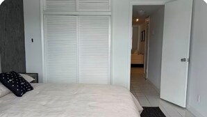 A bedroom with a bed, a dark rug, a white closet, and a hallway leading to a bathroom. - Perfect 1-bedroom apartment with AC and free parking in North Bay Village (North Bay Village)