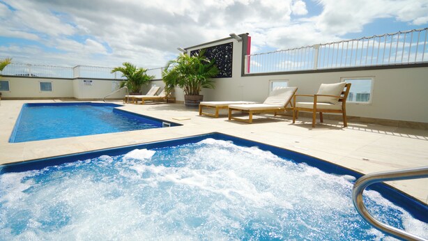 A rooftop pool with a hot tub, lounge chairs, and potted plants. - Tropical Sunsets Studio with rooftop pool in Cairns City (Cairns City)