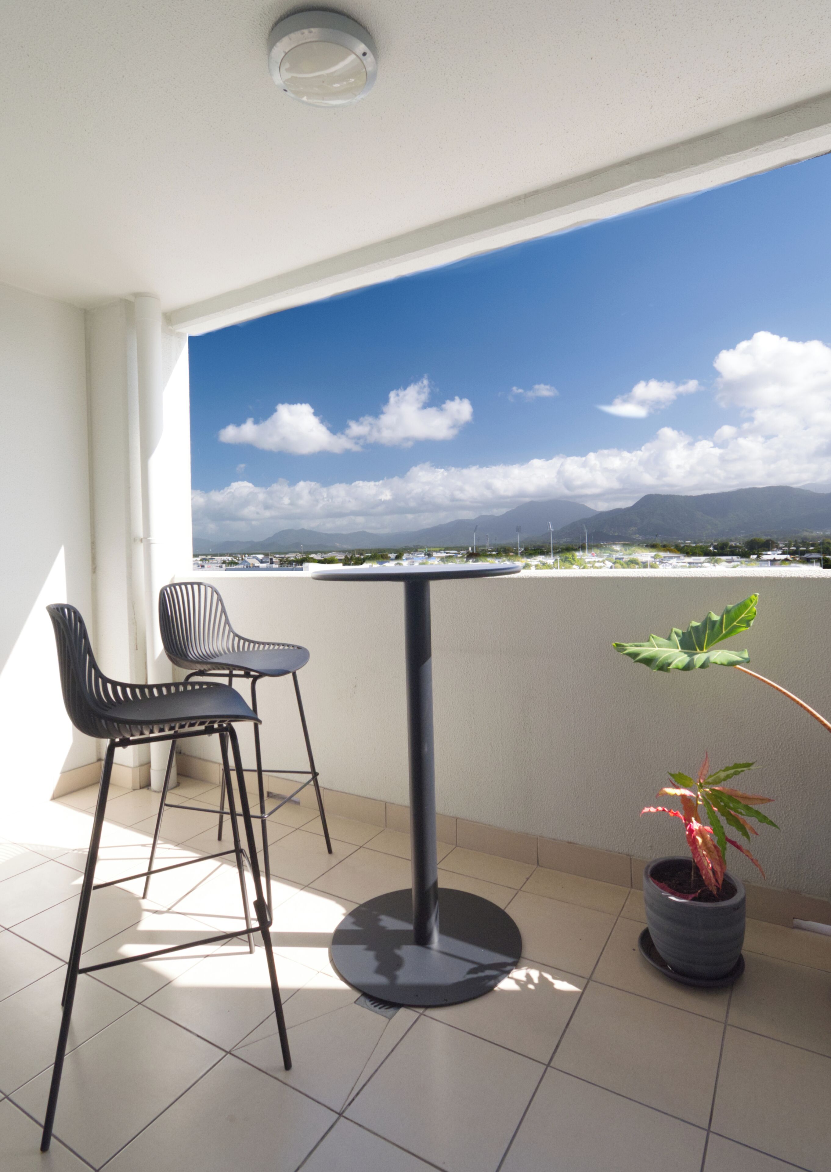 A balcony with two chairs, a table, and a potted plant.