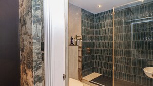 Un baño moderno con cabina de ducha de vidrio, inodoro y lavamanos.