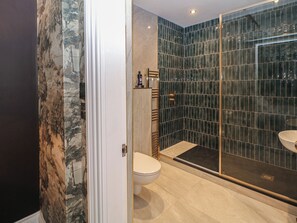Ein Badezimmer mit Duschkabine aus Glas, Toilette und Waschbecken.