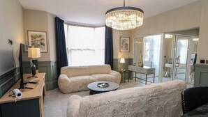 Una sala de estar con sofá, una mesa de centro, un televisor y una lámpara.