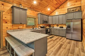 A kitchen with granite countertops, grey cabinets, stainless steel appliances, and a wooden ceiling. - Mountain Creek Oasis | Private Heated Indoor Pool + Hot Tub (Sevierville)